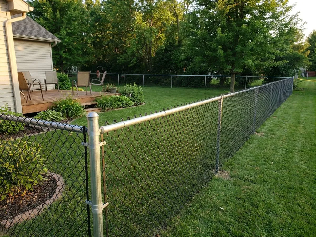 Black vinyl-coated chain link fence enclosing a grassy Midwest yard
