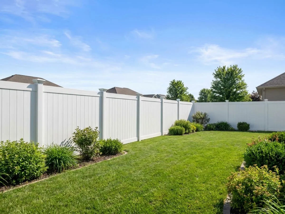 White vinyl privacy fence beside a tidy Midwest backyard lawn